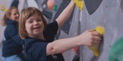 Mädchen an der Kletterwand mit Betreuerin dahinter
