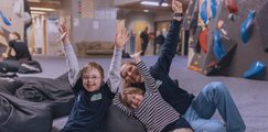 Glücklich und geschafft liegen ein paar Kinder in Sitzsäcken in der Boulderhalle
