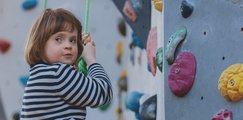 Mädchen an der Boulderwand mit Blick zur Kamera
