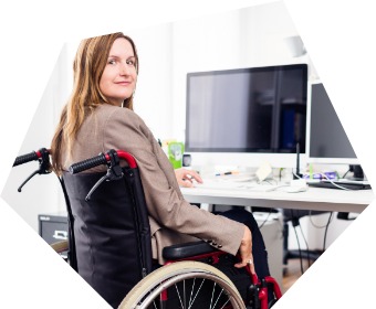 Lächelnde Frau im Rollstuhl am Computerarbeitsplatz