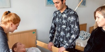 20-jähriges Jubiläum Pflegeausbildung Patientenpuppe mit Auszubildenden